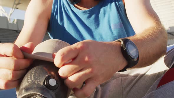 Midsection of caucasian disabled male athlete sitting, putting on running blade alt