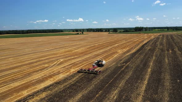The Tractor Works the Soil After the Harvest Aerial View alt