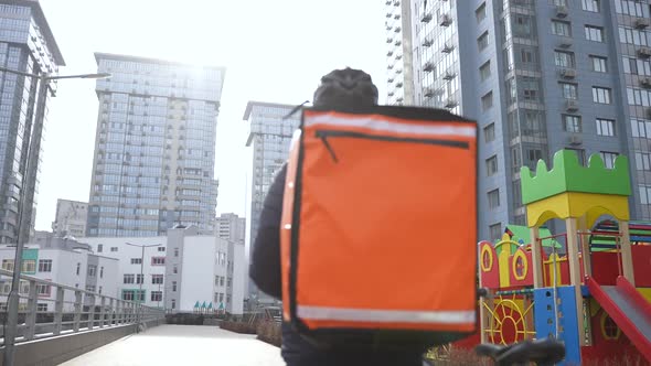 Masked Deliveryman with Thermal Bag Carrying Bike alt