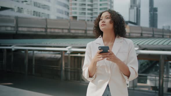 Indian Businesswoman using a mobile phone. Successful Asian Businessperson walking in the street
