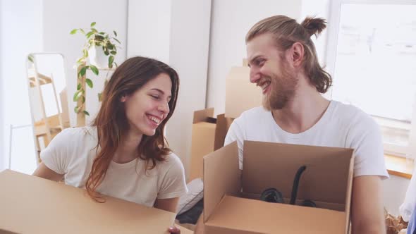 Beautiful Happy Caucasian Pair Holding Boxes with Stuff in Their New Flat in Slowmotion alt