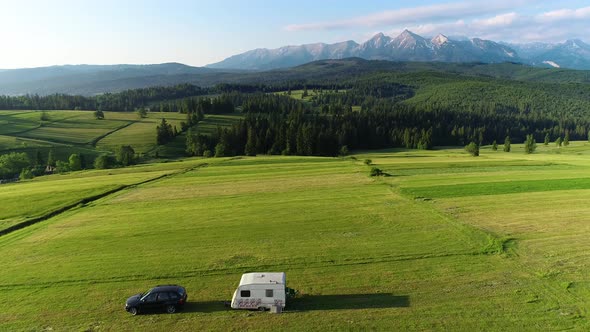 Trailer Caravaning in the mountains. Aerial view of RV car with trailer caravan parked in the meadow