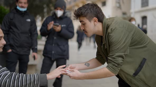 Back View of Magician Showing Magic Tricks to Unknown Person in the Street alt