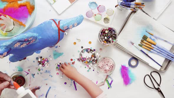 Step by step. Mother and daughter decorating paper mache unicorn together alt