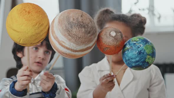 Little Boy and Girl Holding Models of Planets alt