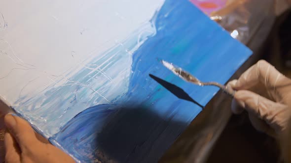 An Artist Drawing an Abstract Picture of Sea Waves Using Palette Knife and Blue Oil Paints