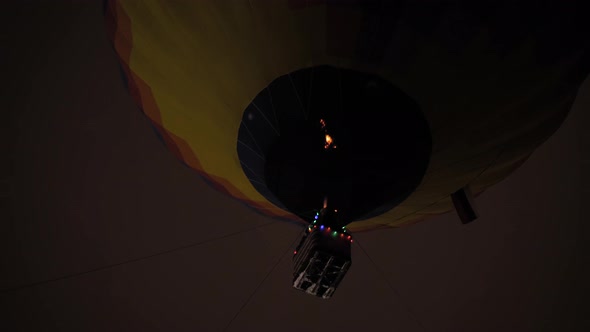 Colorful Hot Air Balloon Flying with Flames Against Dark Sky at Night