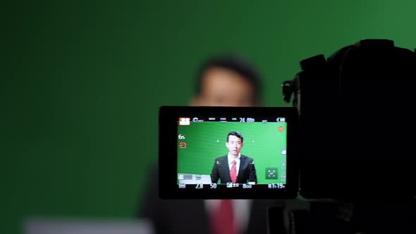 Camera Record Professional Asian Male Anchor Reporting On Green Screen At Home Studio. Chroma Key alt