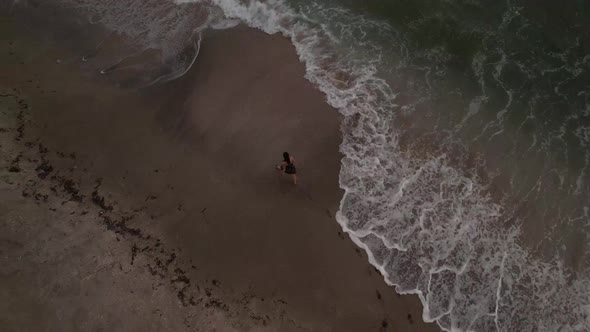 A Girl Walks Along the Sandy Seashore Shooting From a Drone