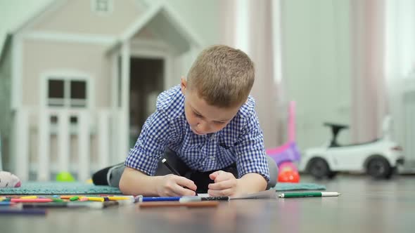 7-Years Old Boy Drawing with Felt Pen on a Floor alt