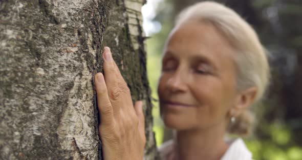 Portrait of Senior Gray Haired Woman Hugging Tree alt