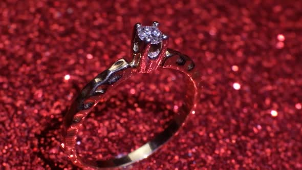 Beautiful Shiny Golden Engagement Ring with Big Gem Diamond on Glitter Red Background alt