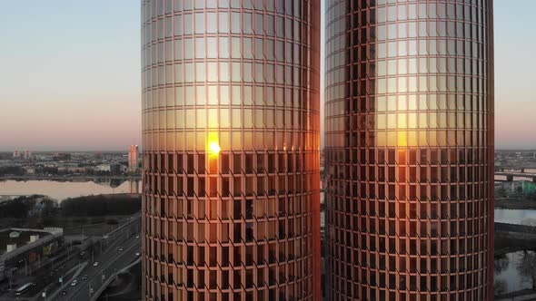 sliding aerial drone view of sunset reflecting on glass windows of twin skyscraper Zunda towers and alt