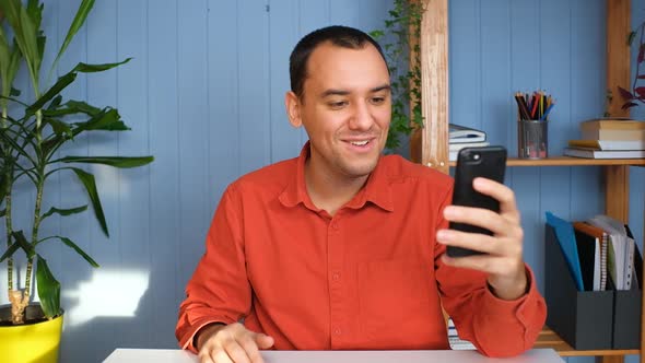 A Young Man Communicates Via Video Link Via Phone with Friends