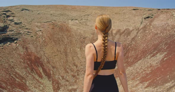 Rear View of Young Woman in Nature Walking in Mountain Volcanic Landscape alt