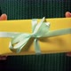 Girl hand holds a gift wrapped in yellow paper tied with white ribbon at a holiday party - VideoHive Item for Sale