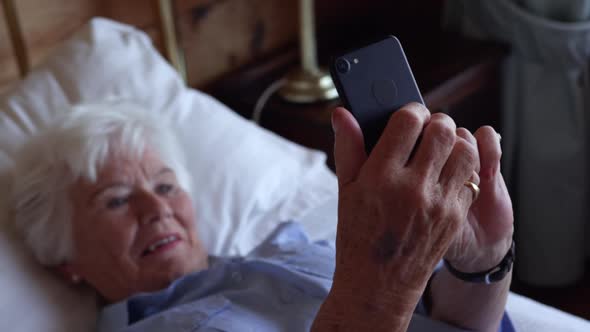 Woman using mobile phone on bed in bedroom at home 4k