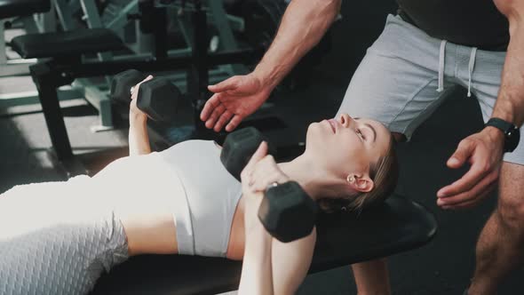 European Blonde Sportswoman Lifting Dumbbells at a Gym alt