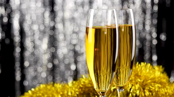 Two glasses of champagne with christmas silver and gold tinsel decoration.