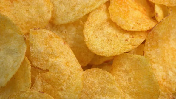 Crispy potato chips rotating in macro. Golden fried potatoes close up. Potato snack for unhealthy alt