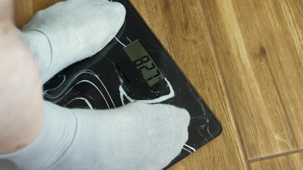 Human Weight Control, Male Legs In Gray Socks Stand On Floor Scales, 82.7 Kg Person