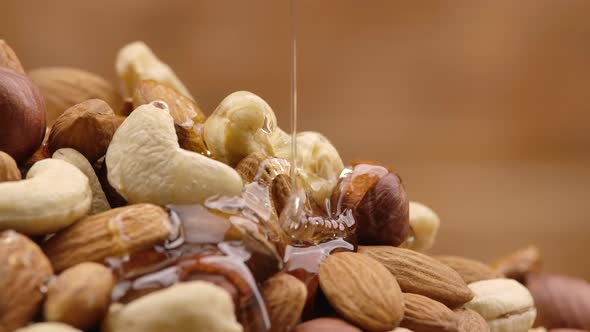 Trickle of Golden Honey Flows Down a Pile of Nuts in Slow Motion alt