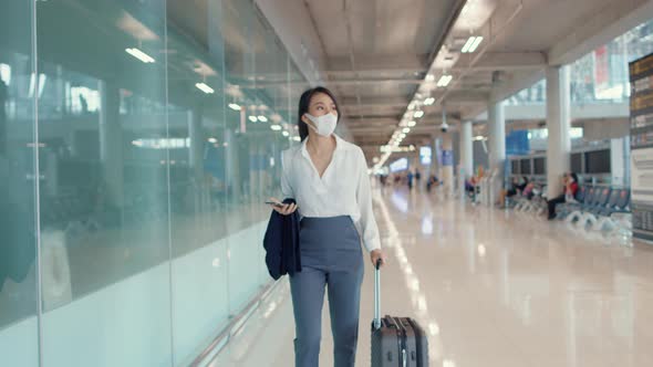 Asian business girl use smart phone for check in boarding pass walk with luggage to terminal