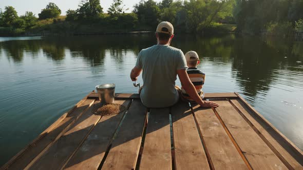 Dad and His Little Son Are Fishing on the Lake