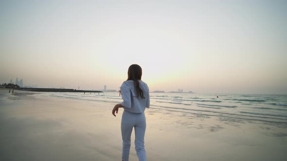 Woman Running on the Beach and Looking Back at the Camera alt