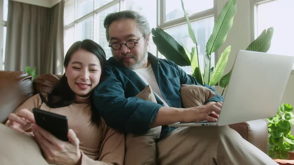 asian female wife hand use tablet shopping online on sofa with husband together