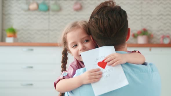 Little girl giving a card to dad for a holiday. The best gift for you alt