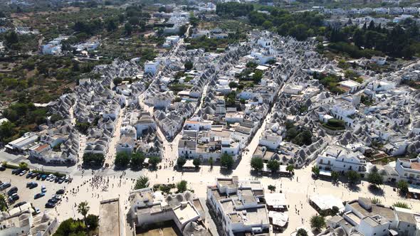 Aerial drone wide shot pushing to beautiful town Alberobello, Italy. whitewashed stone huts with con alt