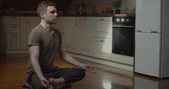 Slow Motion of Serious Young Man Meditating at Home in Cozy Apartment alt
