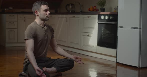 Slow Motion of Serious Young Man Meditating at Home in Cozy Apartment