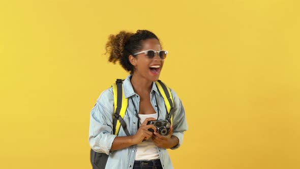 Surprised African American woman tourist backpacker taking photo