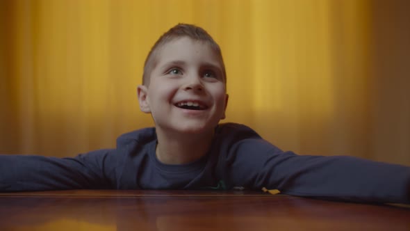 Portrait of autistic boy showing emotions sitting at the desk alt