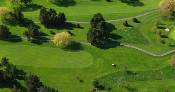 Drone shot of golfers in golf carts seeking out where their golf balls landed. alt