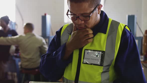 Mixed race man using tablet computer in factory alt