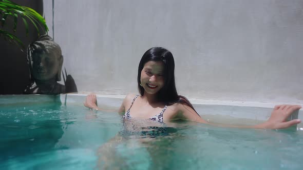 Pretty Asian Girl Alone Smiling In Swimming Pool On a Sunny Day in Slow Motion