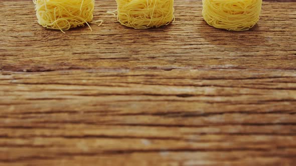 Three roll of spaghetti on wooden table alt