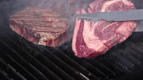 Searing and flipping ribeye steaks on grill alt