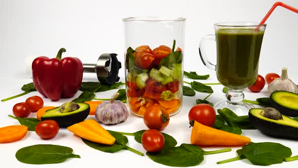 Red bell pepper, fresh spinach leaves, avocado, carrot, tomatoes, garlic and glass with a smoothie