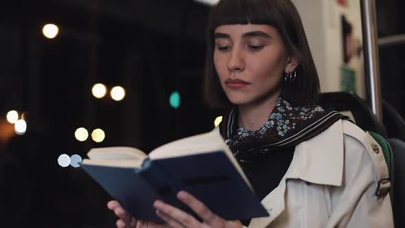 Young Woman or Passenger Reading Book Sitting in Public Transport, Steadicam Shot. Slow Motion. City alt