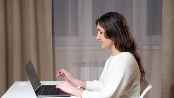 Concentrated Brunette with Long Loose Hair Types on Laptop alt