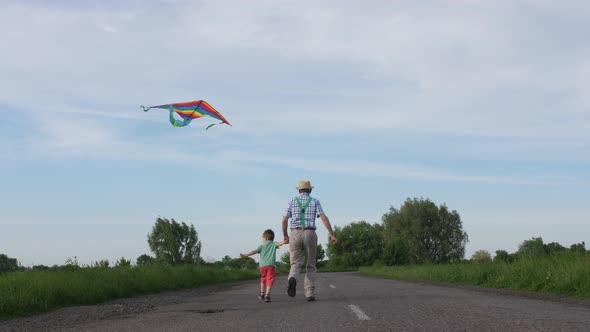 Grandpa with Grandson Flying Kite in Countryside alt