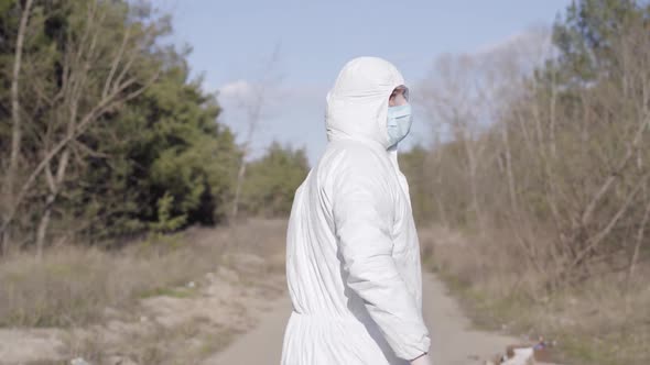 Young Caucasian Sportsman in Safety Suit Running Along Alley in Park. Back View of Man Training alt