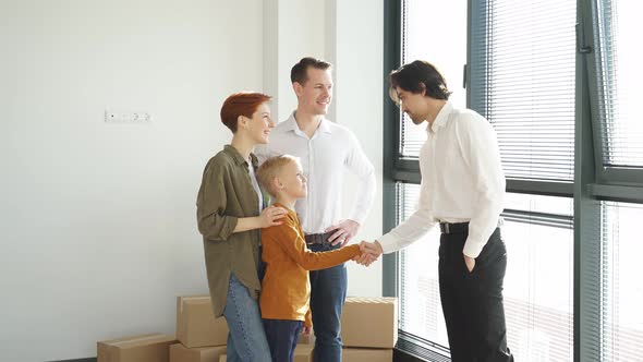 Male Realtor Congratulates Young Caucasian with Signing Rental Agreement Client and Agent Shake alt