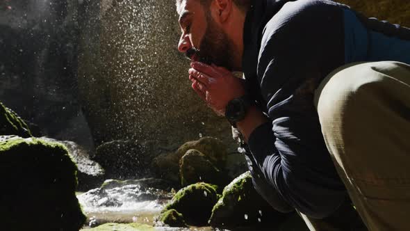 Man Tourist Washes His Face with Mountain Water and Refreshing Himself