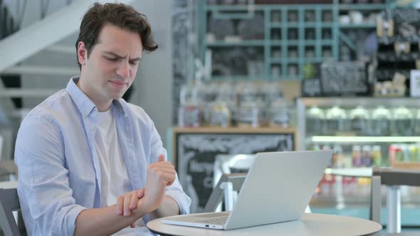 Young Man with Laptop Having Wrist Pain alt