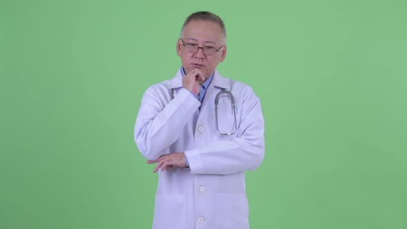 Stressed Mature Japanese Man Doctor Thinking and Looking Down alt